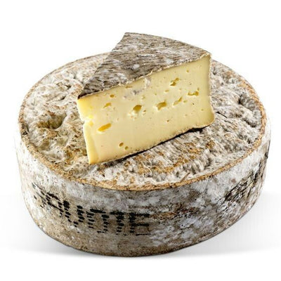 a slice of Tomme de Savoie cheese kept on top of a Tomme de Savoie block